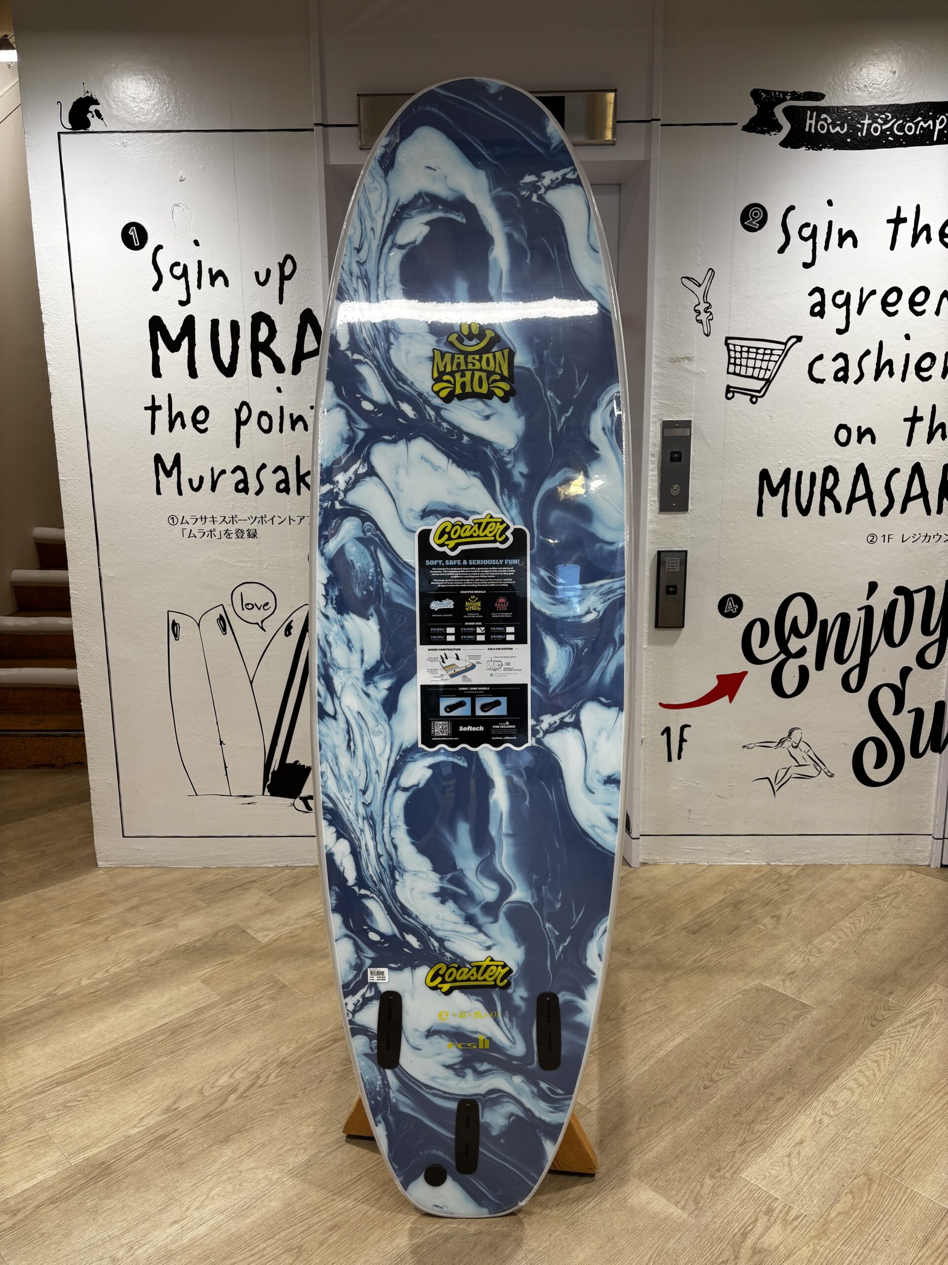 Blue and white marbled surfboard on a stand in a shop, featuring Mason Ho branding.