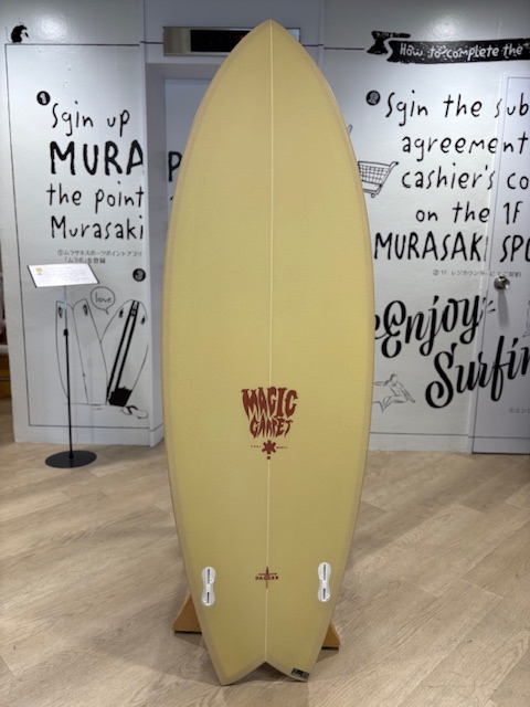 IMG_8799 - SHOP NEWS | ムラサキスポーツオンラインストア 通販 Yellow surfboard on a stand in a shop, with 'Magic Gate' logo near the center bottom of the board.