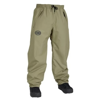 Beige windbreaker pants with elastic cuffs and drawstring waist, logo patch on left thigh, paired with black boots.
