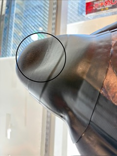 Close-up of a shiny curved metal surface with a circular area showing a dull dent or scratch (defect)