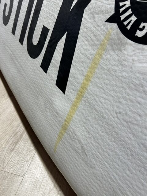 Close-up of a rolled poster on a light wood floor, showing partial black letters and a yellow diagonal stripe.