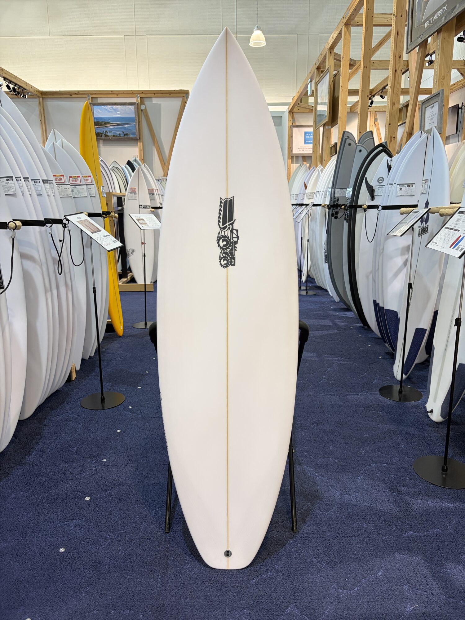 White longboard front-and-center in a surf shop, surrounded by racks of boards on both sides