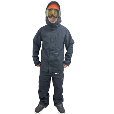 Person wearing a dark waterproof snowsuit with hood and ski goggles, standing with hands in pockets.