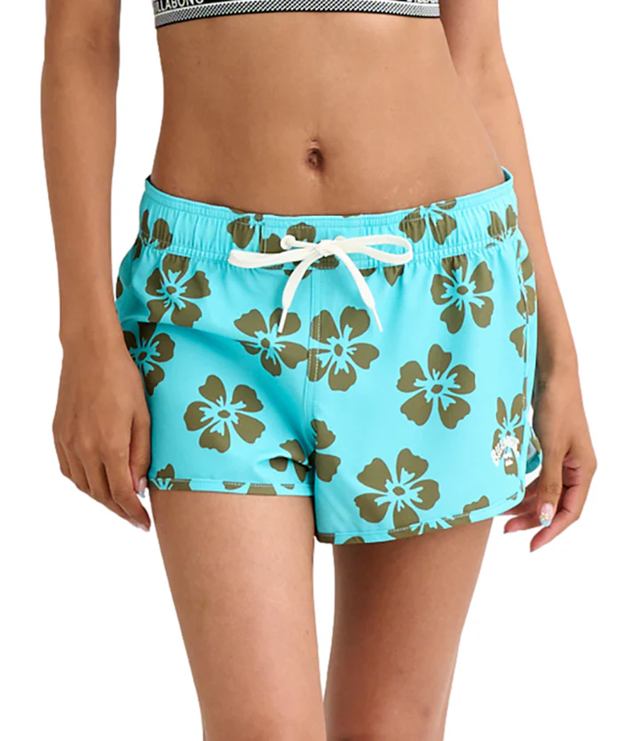 Turquoise floral swim shorts with a white drawstring, shown on a woman’s midsection.