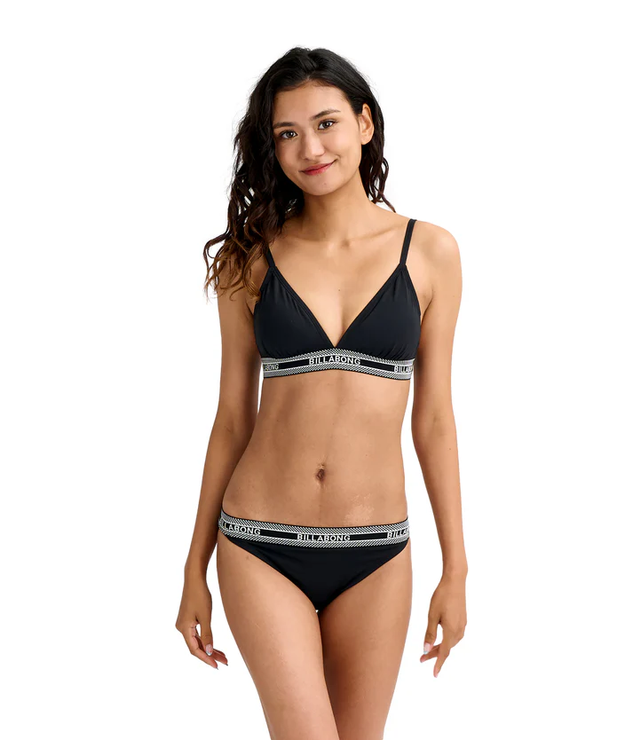 Woman modeling a black bikini with branded elastic bands (Billabong) against a white background, facing forward with a slight smile.