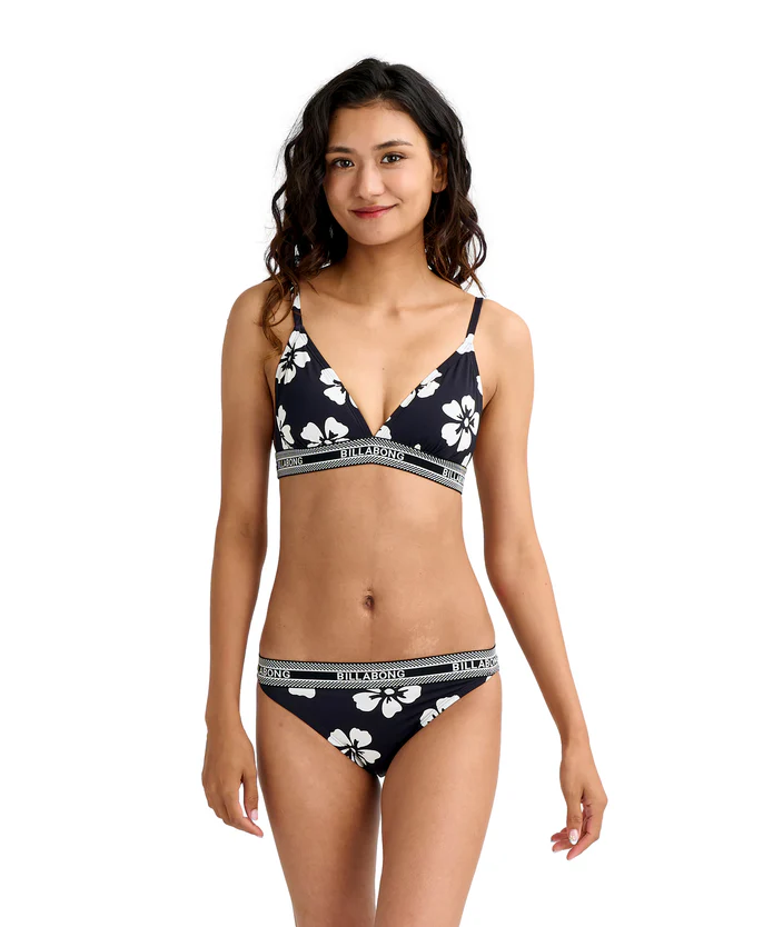 Woman in a navy floral bikini with white hibiscus prints, facing the camera.