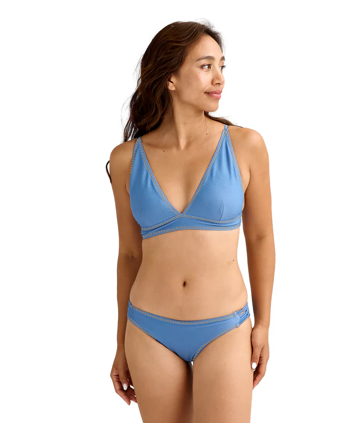 Model wearing a light blue triangle bikini top and matching bottoms, standing and looking to the right.