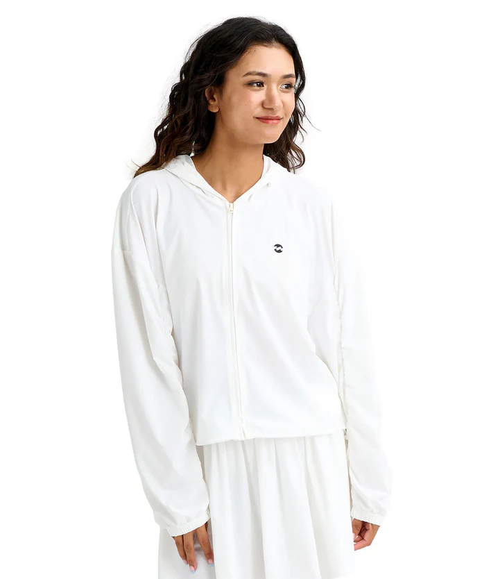 Woman in a white zip-front hoodie with a small logo on the chest, looking to the right.