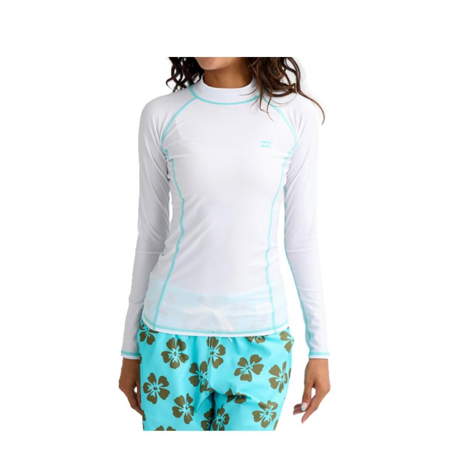 Woman wearing a white long-sleeve rash guard with light blue seams and turquoise floral board shorts.