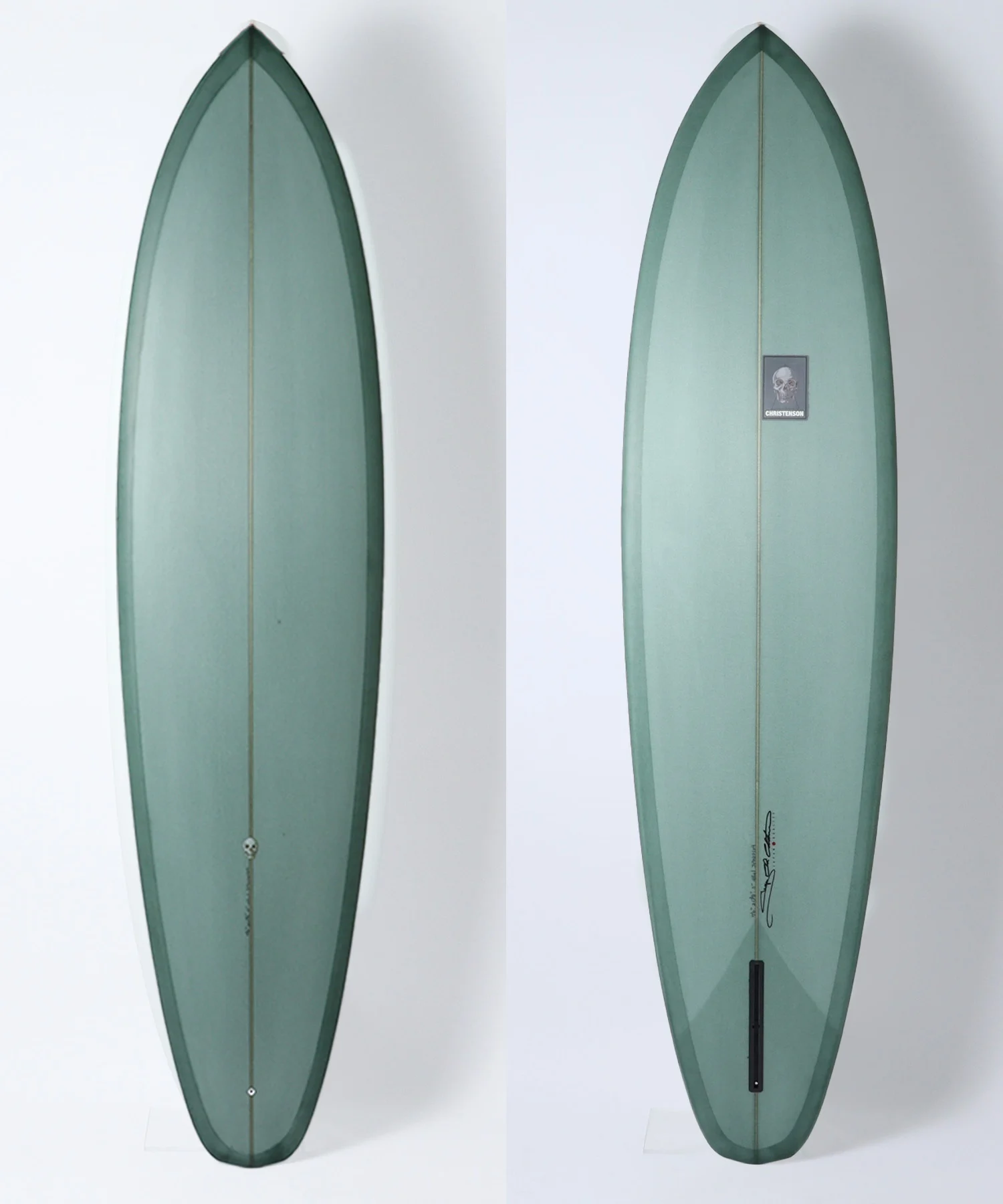 Two vertical teal-green surfboards shown side by side, left plain and right with a small skull-brand sticker reading 'Christenson' mid-length on the board's surface as a reference view pair.