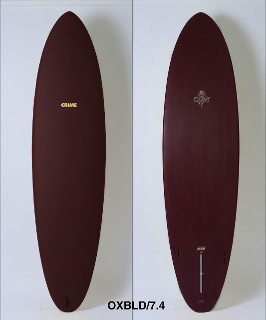 a-EoQ0FtiA - SHOP NEWS | ムラサキスポーツオンラインストア 通販 Two burgundy longboards displayed vertically side by side; left board shows gold 'CRIME' on the deck, right board has a crest on the tail and 'OXBLD/7.4' text below.
