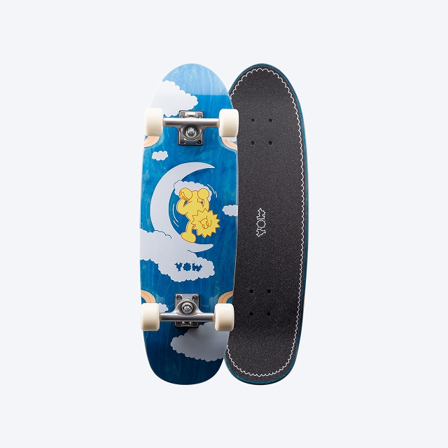 Blue skateboard deck with white clouds and a yellow sun graphic, mounted wheels facing left; right side shows black grip tape with stitched edge.