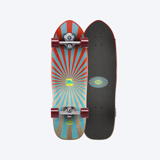Two skateboards standing upright side by side: a colorful sunburst design on the left and a plain black grip tape on the right, with red wheels visible on the left board.