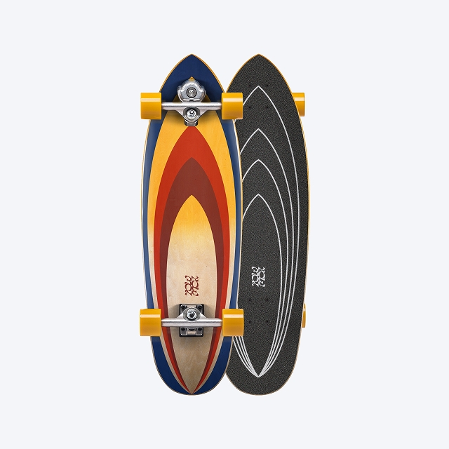 Two longboards stacked back-to-back: one with a sunburst orange–yellow deck and yellow wheels, the other with a black grip-tape deck and white arc graphics.