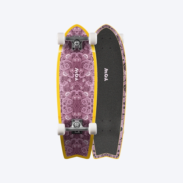Two longboards standing upright side by side: one with a purple ornate deck and yellow trim, the other with black grip tape and a purple edge, both with white wheels and YOW branding.