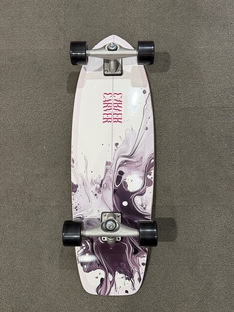 Top-down view of a white longboard with purple marble patterns and black wheels, resting on a gray carpeted surface.