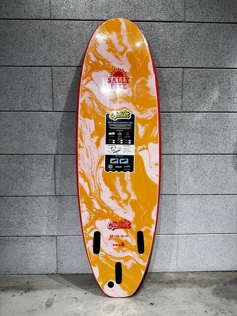 Orange and white marbled wakeboard leaning against a gray tile wall with a center branding label.