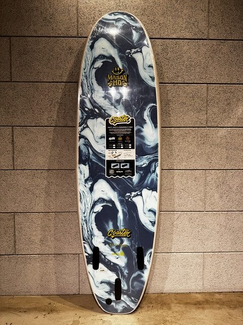 Vertical longboard deck with a black-and-white marble pattern leans against a tiled wall, featuring stickers and a central label.