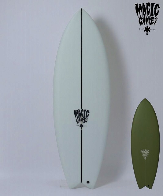Two surfboards propped against a wall: a large pale blue board with a white center seam and a smaller olive green board, both with Magic Carpet logos.