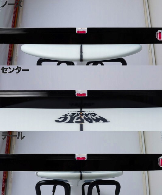 White surfboard on a display rack in a workshop, with black rails and Japanese text panels nearby.