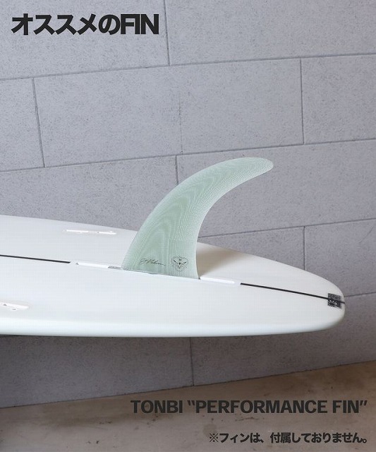 White surfboard with a translucent green performance fin mounted, against a gray wall; TONBI 'PERFORMANCE FIN' branding visible.