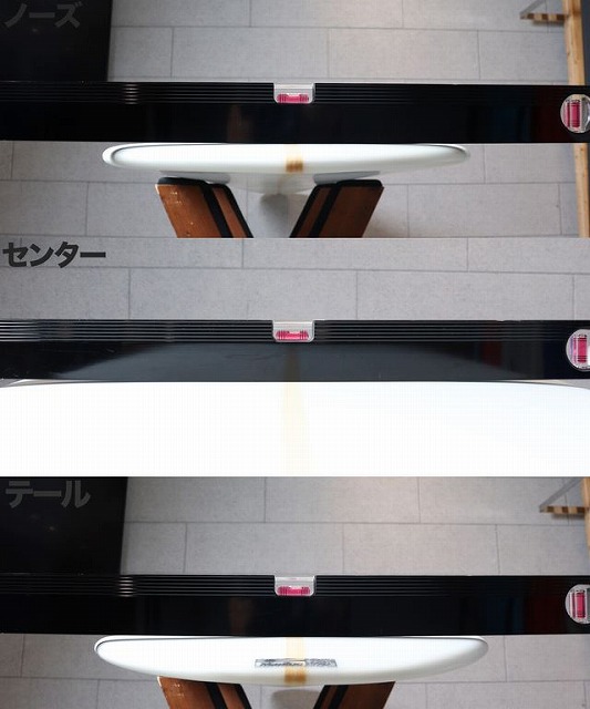 Industrial interior with black glossy panels mounted on a light gray wall, white oval pad between panels, and pink safety labels along the edges.