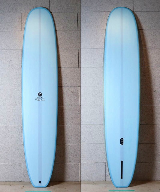 a-WHWp2tsw - SHOP NEWS | ムラサキスポーツオンラインストア 通販 Two light-blue surfboards leaning upright against a tiled wall indoors, a logo visible on the left board.