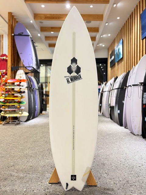 a-image0 - SHOP NEWS | ムラサキスポーツオンラインストア 通販 White surfboard on a wooden stand inside a shop, with an Al Merrick logo and other boards on racks in the background.