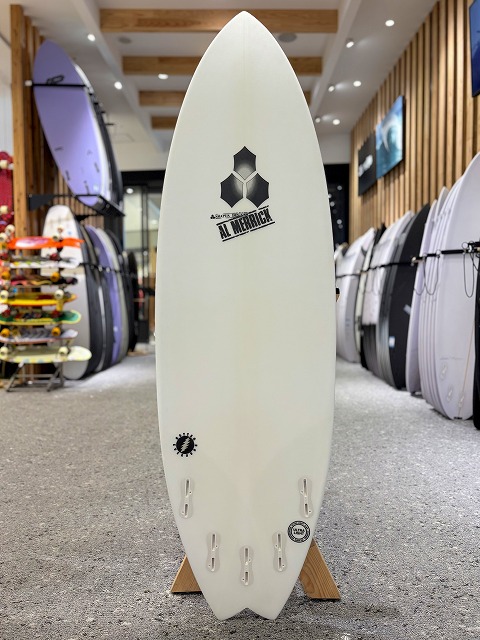a-image1 - SHOP NEWS | ムラサキスポーツオンラインストア 通販 White surfboard on display rack in a shop, with brand logos visible on the board.
