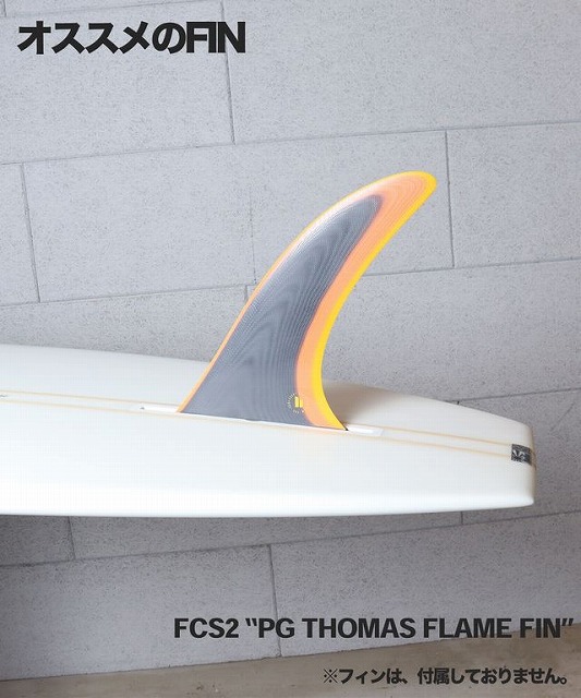 Surfboard with an orange-edged black FCS fin mounted on it, set against a gray wall; Japanese text reads 'おすすめのFIN' and 'FCS2 PG THOMAS FLAME FIN' (fins not included).
