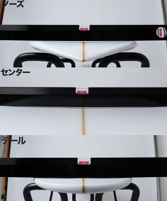 Image shows a white curved object with an orange center line framed by black rails and pink clips, with labels in Japanese marking the nose, center, and tail sections for alignment.