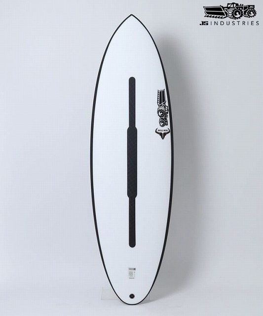 White surfboard standing upright in a bright studio, featuring a long black center fin and the JB Industries logo near the top right.