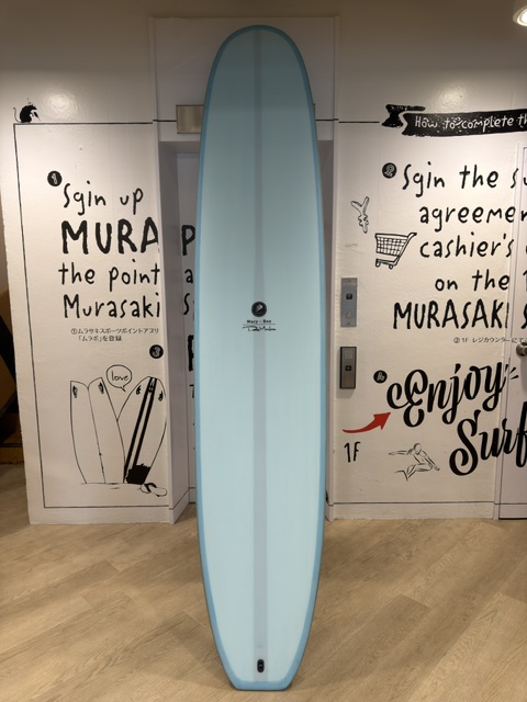 Tall light-blue surfboard standing upright between graffiti-covered doors indoors near a hallway mural.
