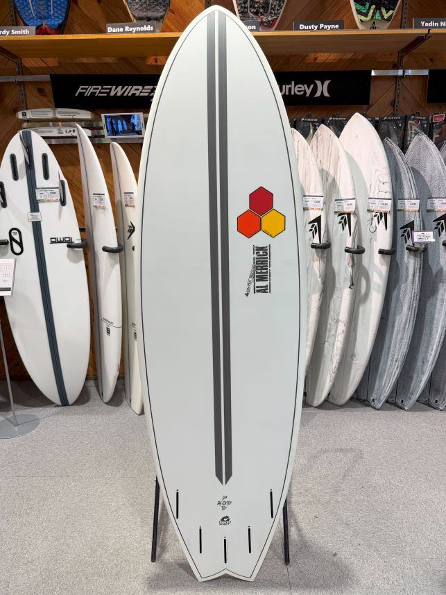 White surfboard on a display rack with a vertical gray stripe and a three-hexagon logo in red, orange, and yellow.