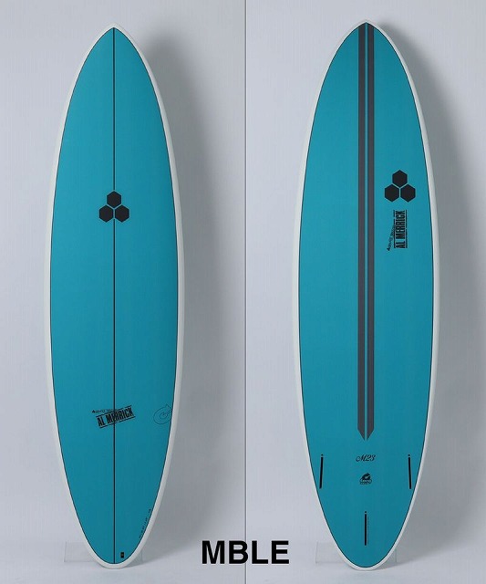 Two turquoise surfboards standing upright against a light background; one has a centered stringer with a small hex logo, the other shows a dark vertical stripe and logo, both labeled MBLE on the deck.