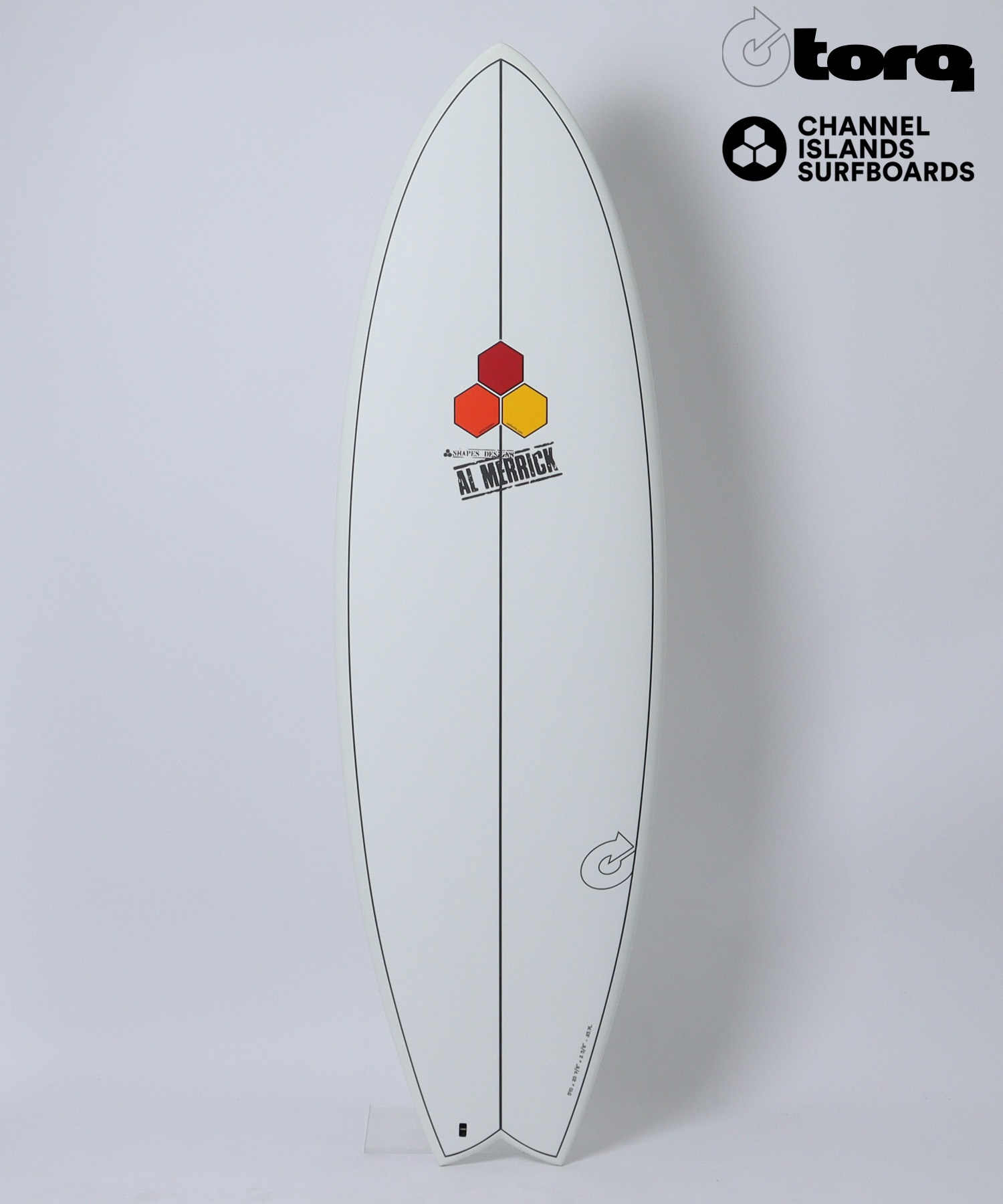 White surfboard standing upright on a light background, with Torq and Channel Islands logos at the top-right and a three-hexagon emblem with 'AL MERRICK' on the board's center.