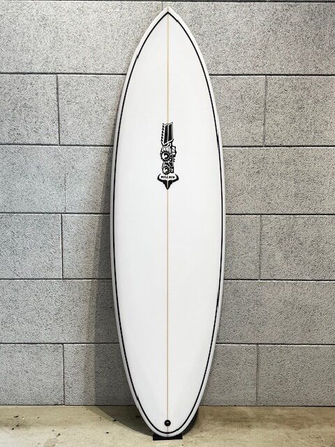 White surfboard standing upright against a gray brick wall, with a tan stringer down the center.
