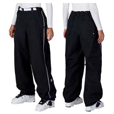 Front and back views of two people wearing black oversized joggers with white sneakers and white tops; pants have white piping along the sides on the left model and a drawstring/elastic waist on the right.