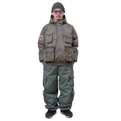 Man in a gray hooded parka with multiple pockets, green cargo pants, beanie and sunglasses, standing against a white background.