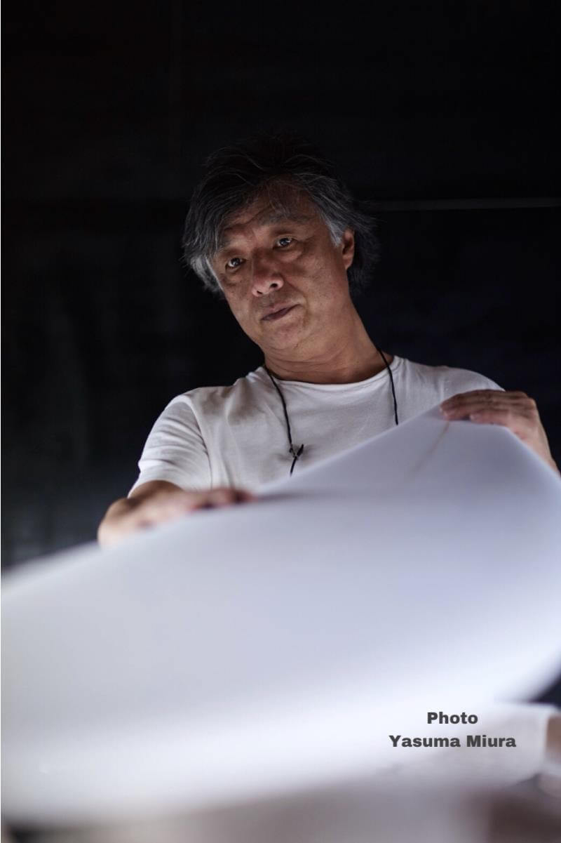 Portrait of a man in a white shirt examining a large white curved surface, with the watermark 'Photo Yasuma Miura' in the bottom right corner.