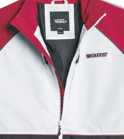 White Vans windbreaker jacket with a red lining and zipper partially open; Vans logo patch on the left chest and a tag visible inside the collar.