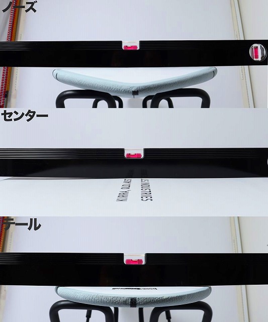 Close-up of a pale blue curved seat with black metal supports, framed by black display bars and white panels with pink connectors.