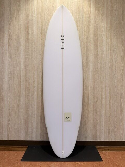 White surfboard standing upright on a black display stand against a wood panel wall indoors.