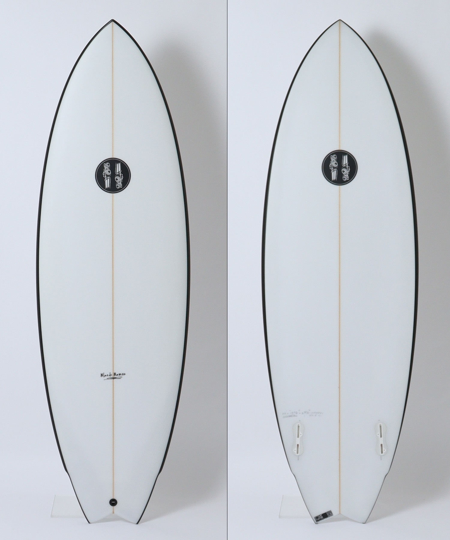 Front and back views of a white board with a brown-orange stringer down the center, black rails, and a circular black logo centered on the deck; photographed against a white background.