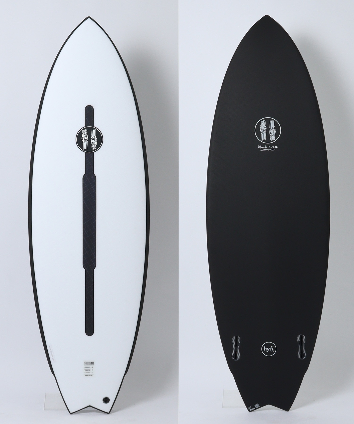 Two surfboards shown vertically side by side: the left board is white with a dark edge and a central black leash pad and logo; the right board is black with a small circular logo near the center.