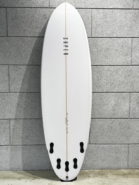 s-IMG_3503 - SHOP NEWS | ムラサキスポーツオンラインストア 通販 White surfboard with a light wooden stringer leaning against a gray brick wall, featuring four black fin boxes at the tail and no fins installed.