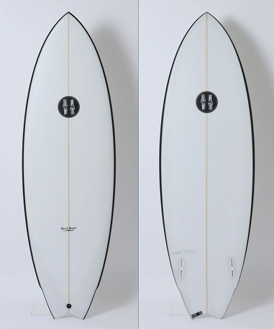 Two white surfboards with black rails stand upright against a light background; left board shows a circular logo midboard, right board shows tail with fin boxes.