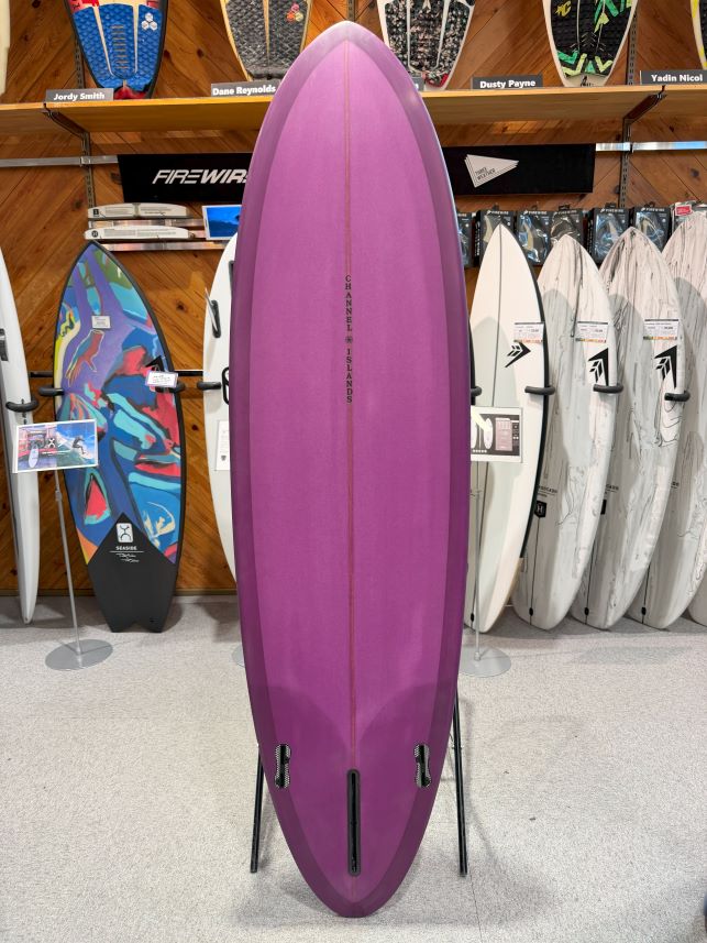 IMG_0226 - SHOP NEWS | ムラサキスポーツオンラインストア 通販 Purple surfboard displayed upright on a stand in a surf shop, with other boards and racks visible in the background.